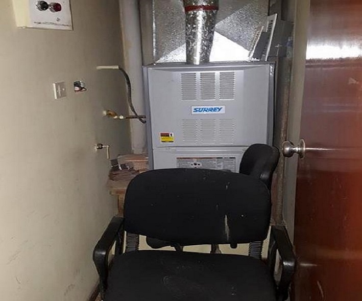 Acceso al sistema de calefacción obstruido por sillas en desuso.  